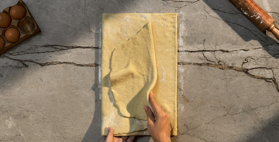 Dough and a rolling pin sit on a countertop of gray Striata porcelain, an alternative to quartz, with a smoky gray base with white streaks.