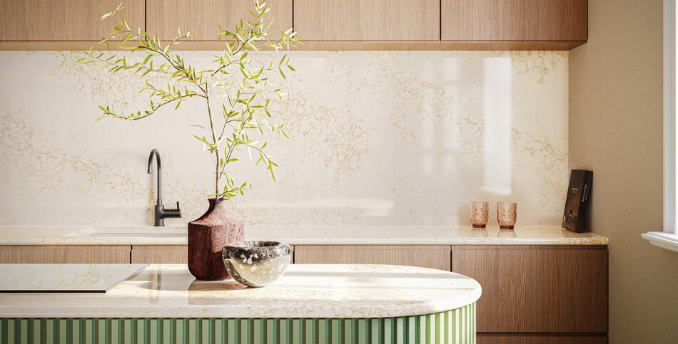 A kitchen countertop and full-height backsplash in a light, veined Goldfinch quartz showing the depth of the counter and island.