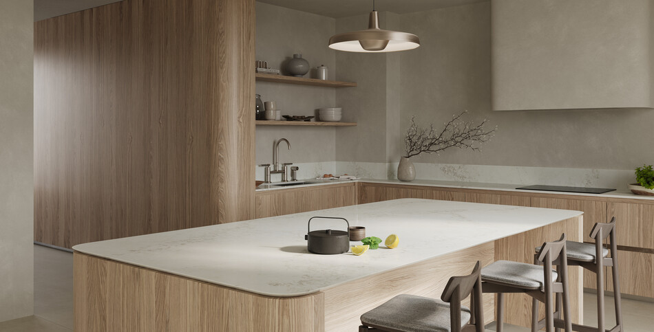 A large kitchen island of ivory Calacatta Lacebound Caesarstone ICON advanced fusion material with taupe and light-gray veins.