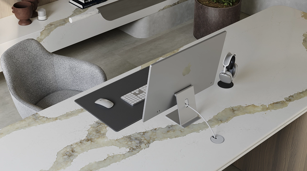 A computer sits on a desk of Calacatta Thyme ICON with translucent sage and gray veining accented by a dark green and white base.