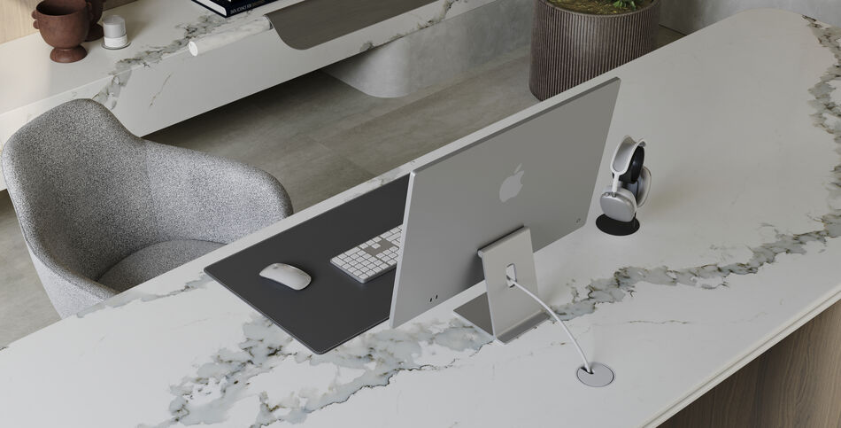 A computer sits on a desk of Calacatta Thyme ICON with translucent sage and gray veining accented by a dark green and white base.