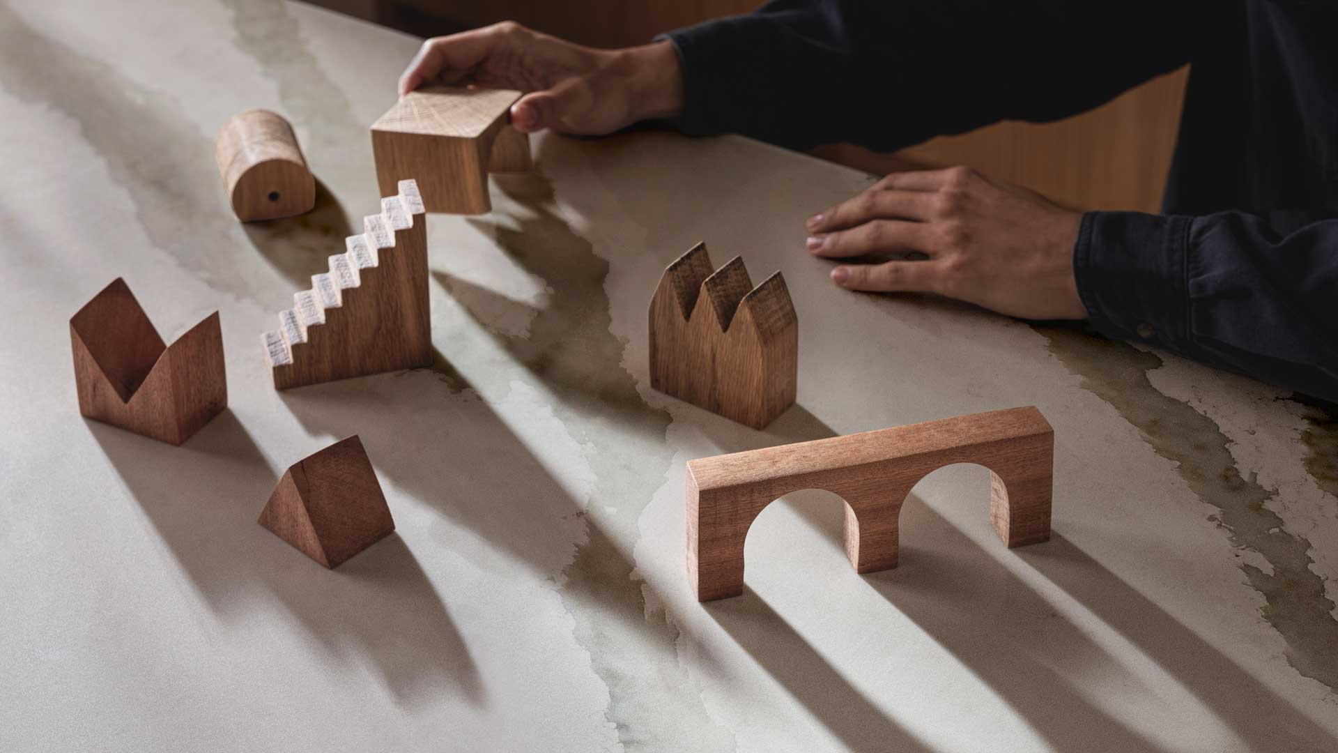 Wooden blocks sit atop an advanced fusion countertop of Calacatta Nobella, a silica-free* quartz alternative, with light-gray veins, accented by warm copper tints.